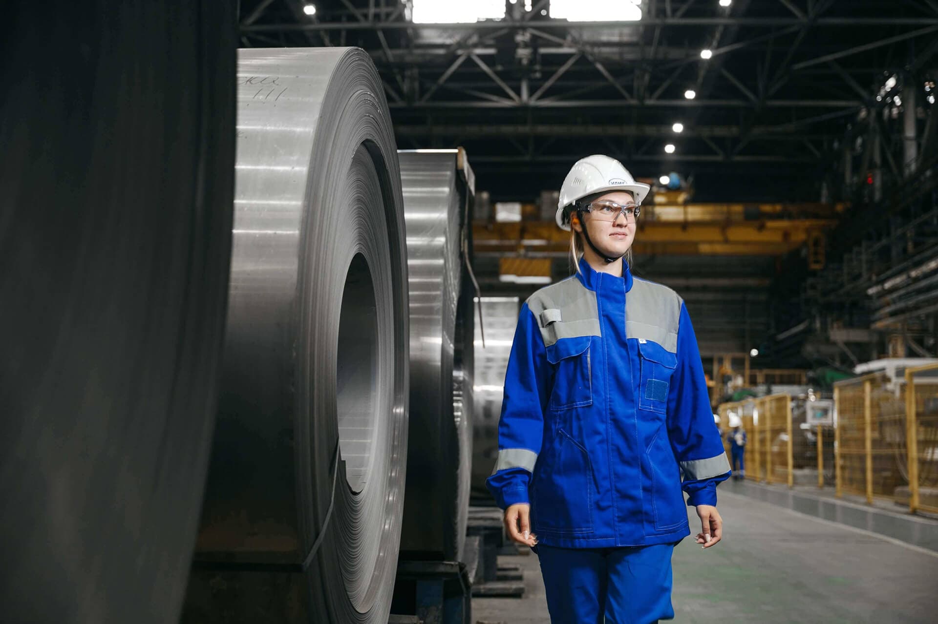 An operator walking down a production aisle past stored material